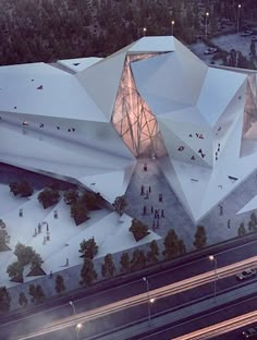 an aerial view of a large white building surrounded by trees and buildings at night time