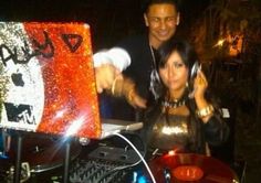 a man and woman standing next to each other in front of a dj's turntable