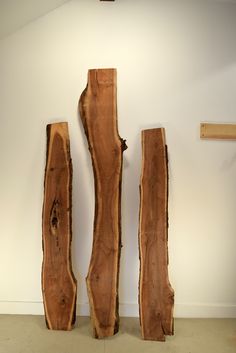 three pieces of wood sitting next to each other on the floor in front of a white wall