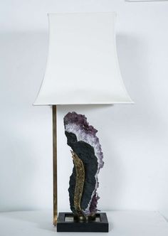 a table lamp with a white shade on it's base and a purple stone in the middle