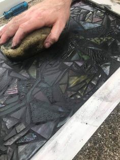 a man is using a sponge to clean the glass on top of a piece of art