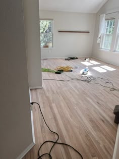 an empty room with hard wood flooring and electrical cords