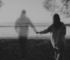 two people holding hands in front of the water