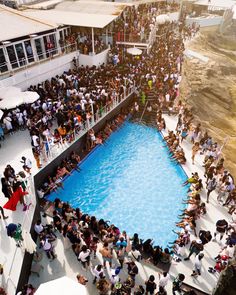 a crowd of people standing around a swimming pool in the middle of an open area