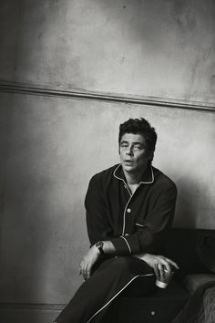 a black and white photo of a man in pajamas sitting on a couch with his legs crossed