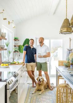two men standing in a kitchen with a dog