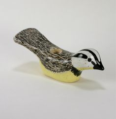 a small bird figurine sitting on top of a yellow base with black and white designs