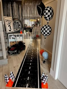 the entrance to a race themed party with balloons and checkered flags hanging from the ceiling