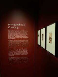 a red wall with black and white photographs on it's sides in a museum