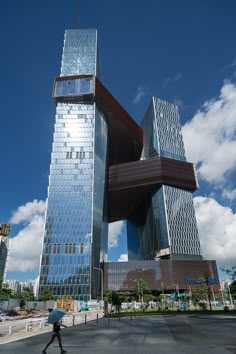 a person walking in front of a very tall building that is shaped like a bird's nest