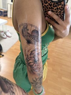 a woman with a tattoo on her arm holding a cell phone