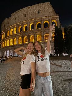 two girls standing in front of the colossion at night with their arms around each other