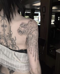 the back of a woman's shoulder with an angel tattoo