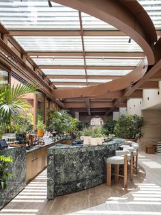 the inside of a restaurant with tables and chairs, plants on the counter and potted trees in the background