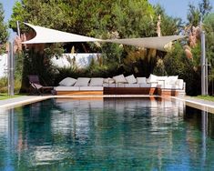 an outdoor swimming pool with lounge chairs and umbrellas next to the water's edge