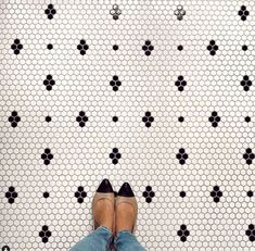 a woman's feet in high heels standing on a tiled floor with black and white designs