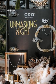 an unmasking night sign surrounded by feathers and other items in front of it