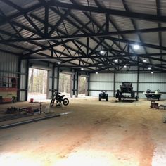 the inside of a building with several vehicles parked in it's garage area and lights on
