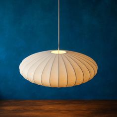 a white lamp hanging from a ceiling in a room with blue walls and wood flooring