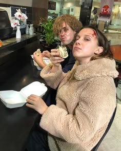 a man and woman sitting at a table with food in front of them on their hands