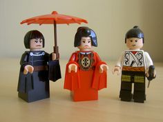 three legos are standing next to each other with an umbrella on top of them
