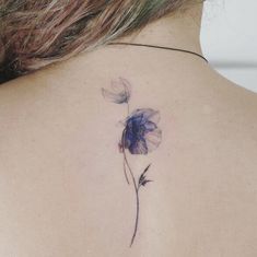 the back of a woman's neck with a flower tattoo on it