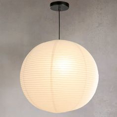 a round light hanging from the ceiling in a room with concrete walls and flooring