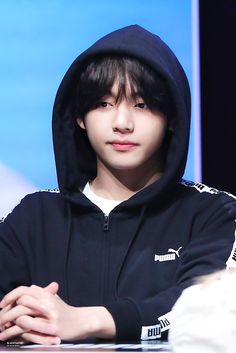 a young man sitting at a table with his arms crossed and wearing a black hoodie