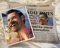 two newspapers laying on top of a bed next to each other with pictures of men smiling
