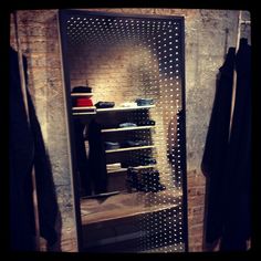 a closet with clothes hanging on the wall and an open door that has holes in it