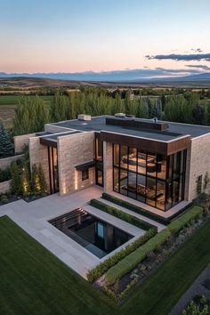 an aerial view of a modern home in the countryside at dusk with its pool and landscaping