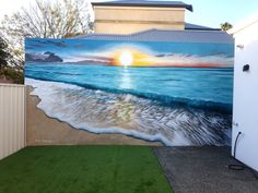 a painting on the side of a building with waves coming in to shore and sun setting