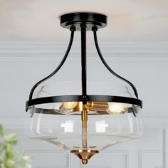 a glass light fixture hanging from the ceiling in a room with white walls and flooring