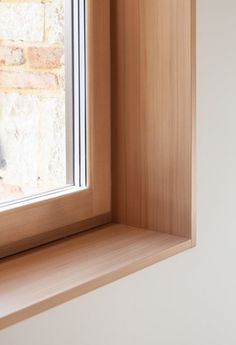 a cat sitting on the ledge of a window sill next to a brick wall