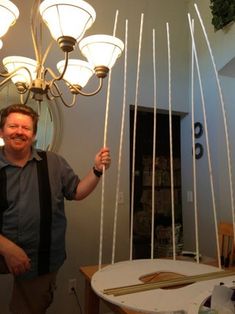 a man standing in front of a chandelier that has lights hanging from it