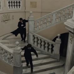 three people are walking up the stairs in an old building with white railings and wrought iron balconies
