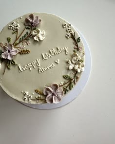 a birthday cake decorated with flowers and the words happy birthday annie on it's side