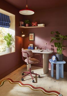 a room with a desk and chair in the corner next to a potted plant