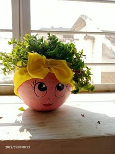 a potted plant with a face painted on it sitting on a window sill