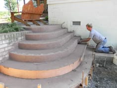 a man working on concrete steps in front of a house