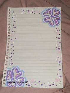 a piece of lined paper with purple and blue flowers on it sitting on a bed