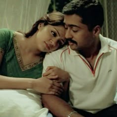 a man sitting next to a woman on top of a bed