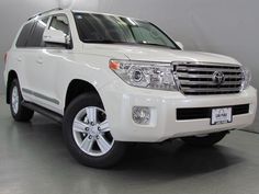 a white toyota land cruiser is parked in a room with gray walls and flooring