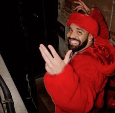 a man in a red outfit waving at the camera