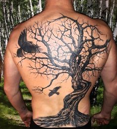 the back of a man with a tree and two birds tattoo on his upper body