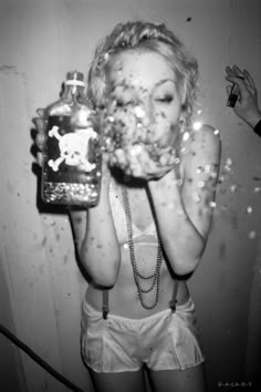 a woman holding a bottle in front of her face with confetti all over it
