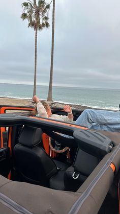 a man laying in the back of a truck on top of a beach next to palm trees