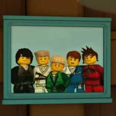 the legos are standing together in front of a blue framed photo on a wall