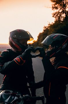 two people wearing helmets are sitting on a motorcycle and one person is holding the handlebars