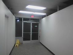 an empty hallway with white walls and black doors